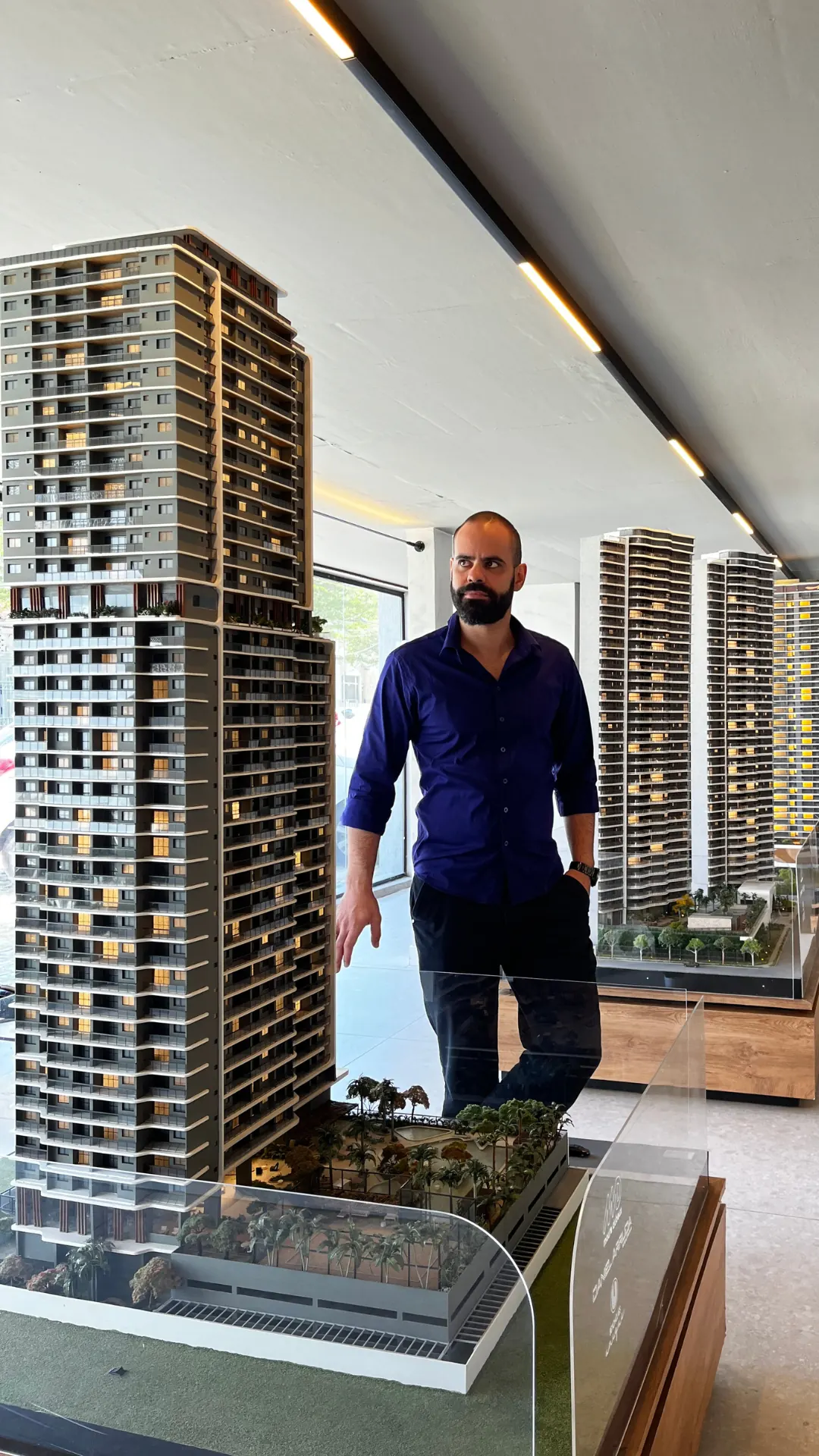 Fundador da ROTNA de camisa azul ao lado da maquete de um empreendimento.